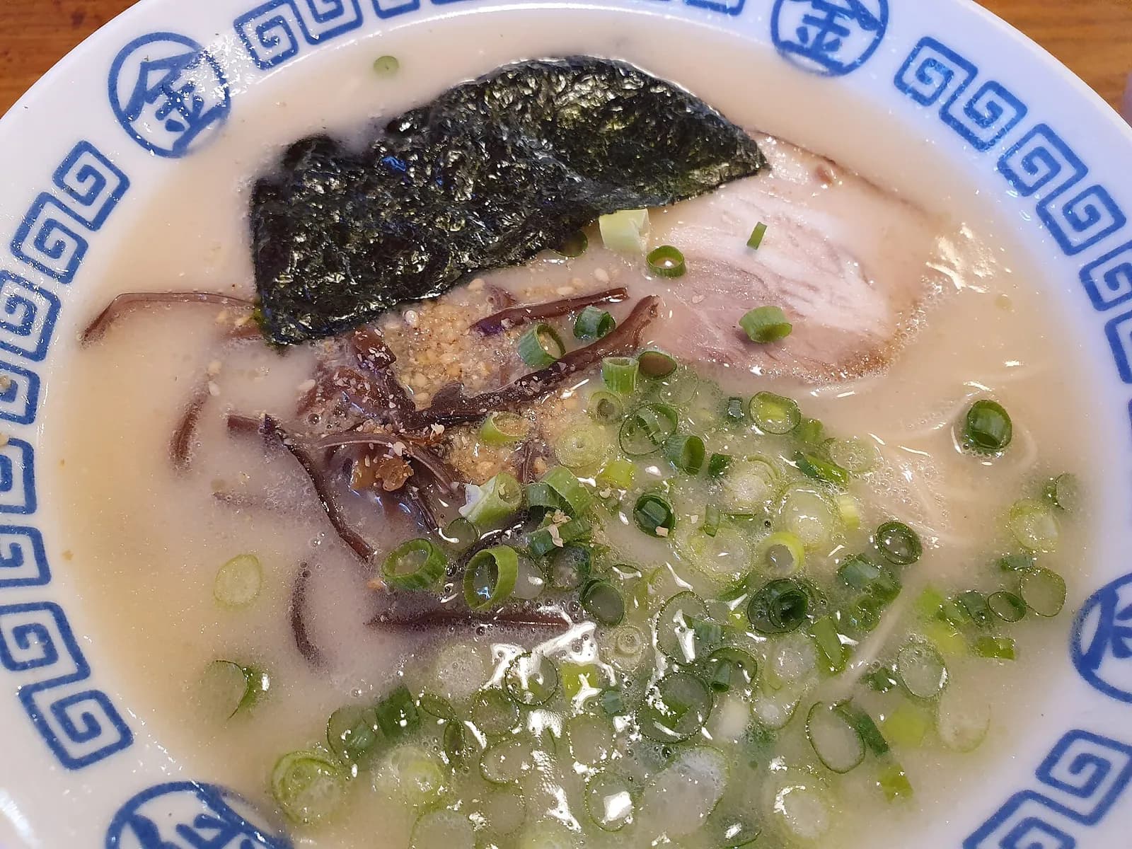 Een kom tonkotsu-ramen met varkensbuik, ei en lente-ui in een rijke, romige bouillon